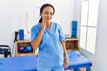 Young african american woman working at pain recovery clinic touching mouth with hand with painful expression because of toothache or dental illness on teeth. dentist