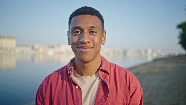 African American man stands smiling against blurry beach