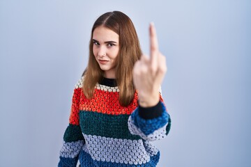 Young hispanic girl standing over blue background showing middle finger, impolite and rude fuck off...