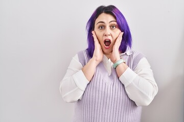 Plus size woman wit purple hair standing over white background afraid and shocked, surprise and amazed expression with hands on face