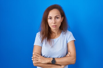 Brunette woman standing over blue background looking sleepy and tired, exhausted for fatigue and hangover, lazy eyes in the morning.