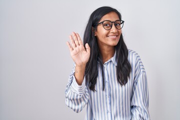 Young hispanic woman wearing glasses waiving saying hello happy and smiling, friendly welcome gesture © Krakenimages.com