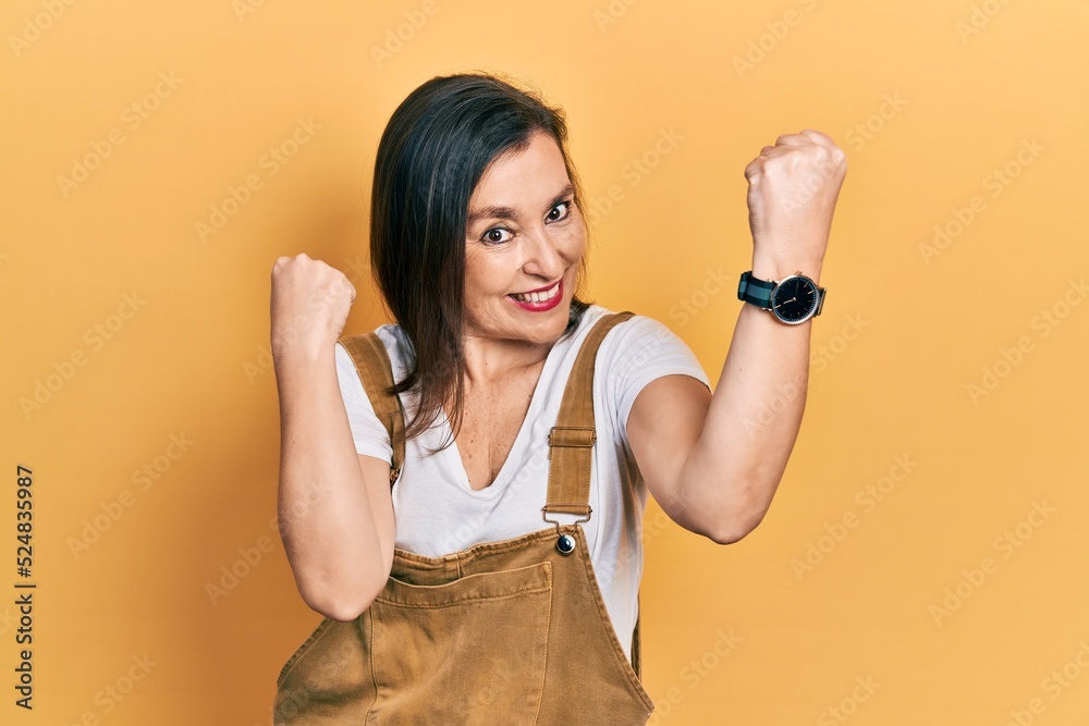 Poster Middle age hispanic woman wearing casual clothes screaming proud, celebrating victory and success very excited with raised arms