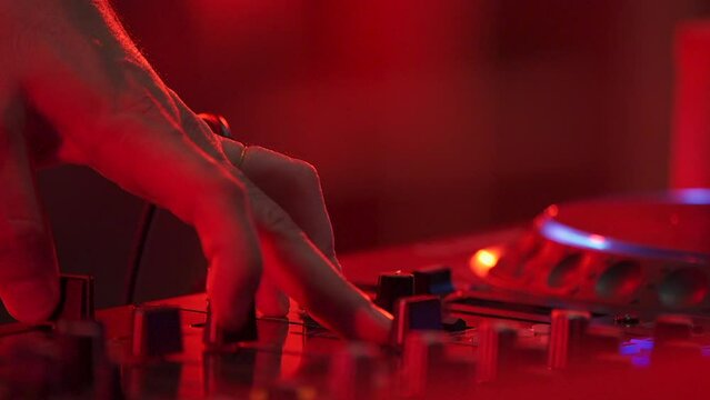 DJ hand and finger are closed up between he controls the Mixer Sound Console board Machine.