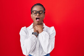 African woman with braids standing over red background shouting and suffocate because painful strangle. health problem. asphyxiate and suicide concept.