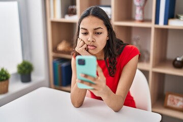 Young african american woman using smartphone with serious expression at home