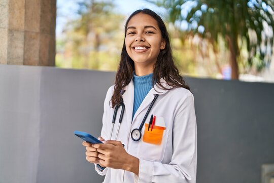 Young african american woman doctor using smartphone at street