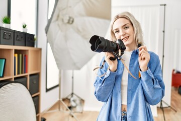 Beautiful blonde woman working as professional photographer at photography studio. Standing holding sdxc storage memory card