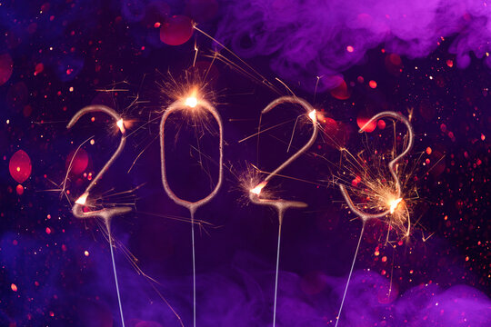 2023 Happy new year Silvester greeting card banner with burning golden sparklers shiny glitter bokeh and colorful smoke