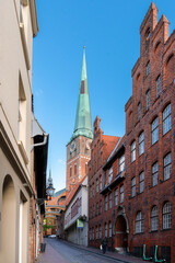 Fototapeta na wymiar Street in Lübeck with tradional buildings und view to the tower of the church St. Jakobi