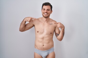 Fototapeta na wymiar Young hispanic man standing shirtless wearing underware looking confident with smile on face, pointing oneself with fingers proud and happy.
