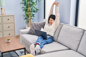 Young chinese woman watching movie sitting on sofa at home