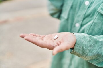 Young chinese woman holding pills at street