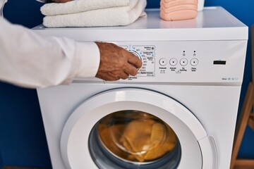 Senior man turning on washing machine at laundry room