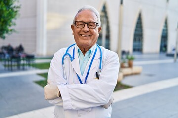Senior man wearing doctor uniform standing with arms crossed gesture at street