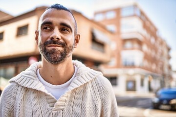 Handsome middle age man with beard standing happy and confident at the city