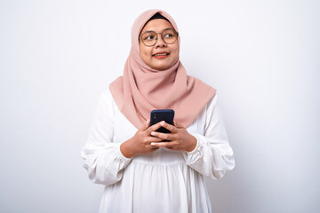 Young asian muslim woman smiling using mobile phone
