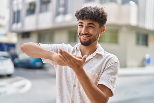 Young arab man smiling confident doing spend money gesture at street