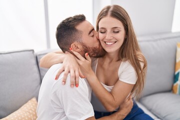 Obraz na płótnie Canvas Man and woman couple sitting on sofa kissing at home