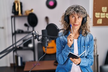 Middle age woman singer composing song at music studio