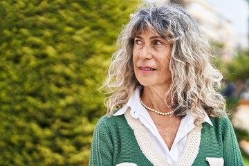Middle age woman with relaxed expression standing at park