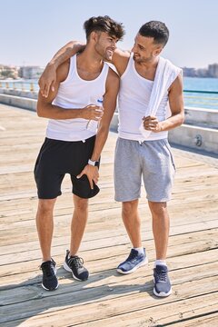 Two hispanic men sporty couple smiling confident and hugging each other standing at seaside