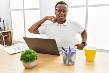 Young african man working at the office using computer laptop stretching back, tired and relaxed,...