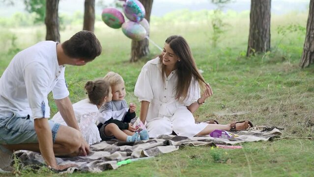 Happy family relax lying picnic blanket. Parents rest on grass with two kids