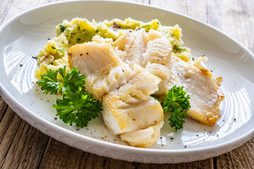 Fish dish - fried cod fillet with potato puree on wooden table
