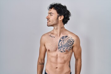 Fototapeta premium Hispanic man standing shirtless looking away to side with smile on face, natural expression. laughing confident.