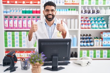 Hispanic man with beard working at pharmacy drugstore success sign doing positive gesture with...