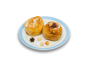 baked apples on plate isolated on white. Fruit dessert stuffed with walnuts, pine nuts and cone