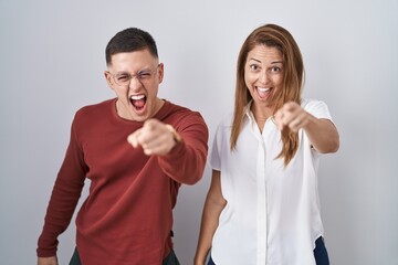 Mother and son standing together over isolated background pointing displeased and frustrated to the camera, angry and furious with you