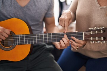 Fototapeta na wymiar Man and woman musicians having classic guitar lesson at music studio