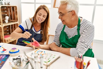 Two middle age artists smiling happy painting hands at art studio.