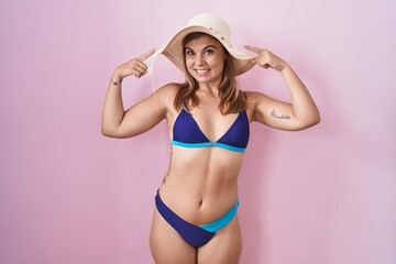 Young hispanic woman wearing bikini over pink background smiling pointing to head with both hands finger, great idea or thought, good memory