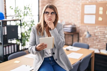 Young hispanic woman working at the office wearing glasses thinking worried about a question, concerned and nervous with hand on chin