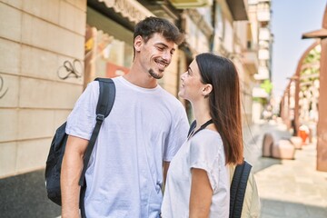 Man and woman couple wearing backpack hugging each other at street