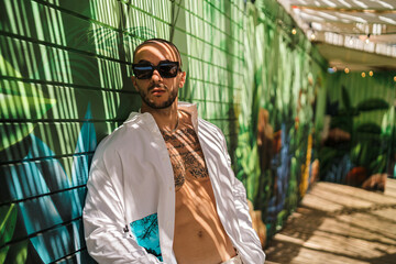 Chico joven guapo musculoso en zona de sombra con gafas de sol sonriendo, posando y tomándose selfies