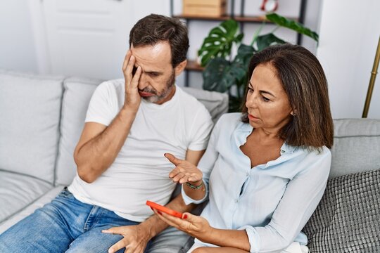 Middle age man and woman couple with problem for infidelity using smartphone at home