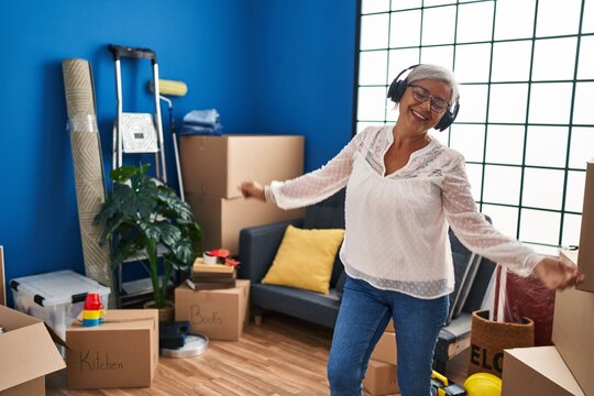 Middle Age Woman Listening To Music And Dancing At New Home