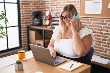 Young woman business worker using laptop talking on smartphone at office