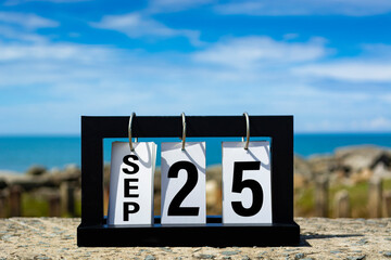 Sep 25 calendar date text on wooden frame with blurred background of ocean.