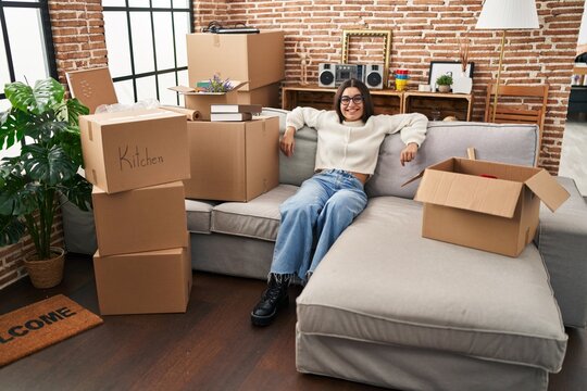 Young hispanic woman smiling confident relaxed sitting o sofa at new home