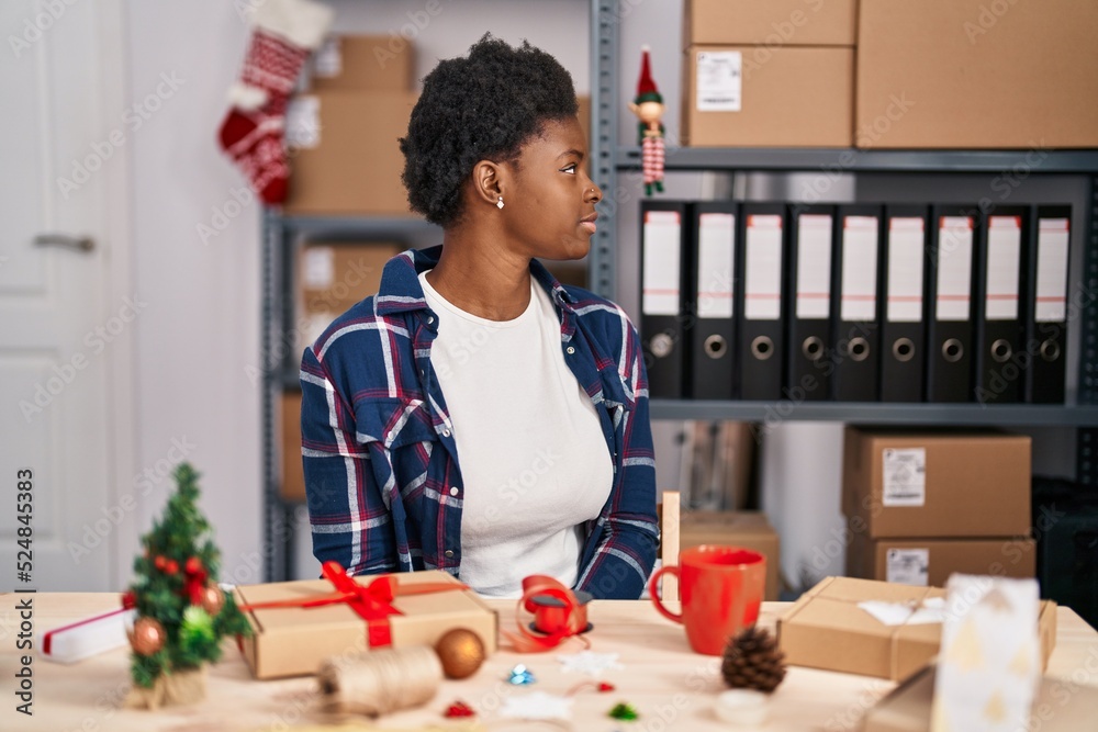 Sticker African american woman working at small business doing christmas decoration looking to side, relax profile pose with natural face with confident smile.