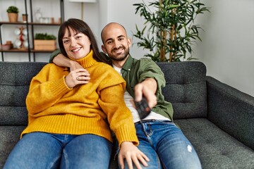 Young hispanic couple smiling happy watching movie sitting on the sofa at home.