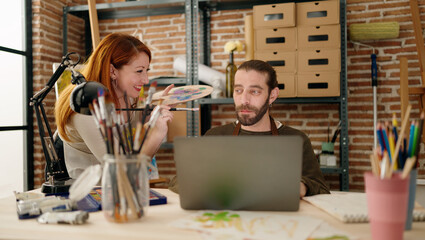 Man and woman couple using laptop and drawing at art studio