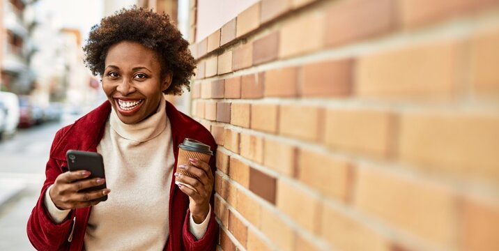 Beautiful business african american woman with afro hair smiling happy and confident outdoors at the city using smarpthone