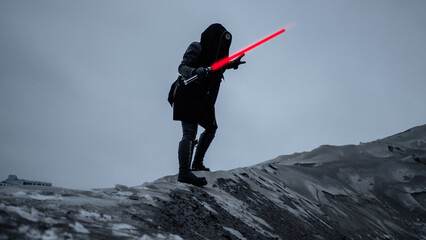 A fantastic assassin in a black suit with a red laser sword against a gray gloomy landscape of a...