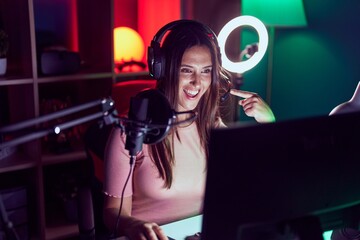 Young brunette woman playing video games smiling happy pointing with hand and finger © Krakenimages.com